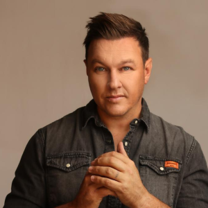 Arno Jordaan performing live on stage with microphone in hand